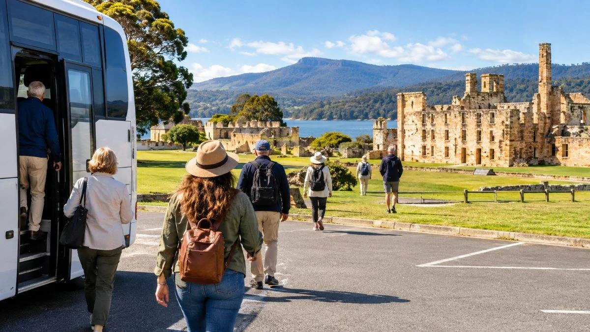 Visitors stepping off a tour coach beside sandstone ruins on a green lawn